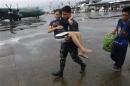A military personnel carries a woman who had injured her leg, to a military C-130 aircraft leaving for Manila, after super typhoon Haiyan battered Tacloban City in central Philippines