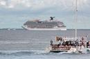Tourists enjoy a ride on a catamaran as cruise ship Carnival Magic is seen near the shores of Cozumel