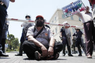 <p> A municipal worker sits in front of the entrance of Greek Parliament during a protest in central Athens, on Tuesday, July 9, 2013, as a demonstrator holds a banner which reads "Greek Parliament thieves". Greek municipal workers went on strike for the second day Tuesday to protest their inclusion in a government plan to reduce the number of civil servants and meet criteria for the country to continue receiving vital funds from its international bailout. (AP Photo/Petros Giannakouris)