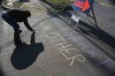 A volunteer writes messages of solidarity with chalk on the sidewalk of W. Florissant