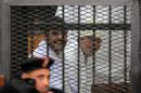 Egyptian activicts Ahmed Douma (left) and Ahmed Maher, the founder of the April 6 youth movement that led the revolt against Hosni Mubarak, stand in the dock during their trial on December 22, 2013 in Cairo