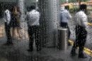 Office workers are reflected in rain-covered window at lobby of building in Singapore's financial district