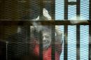 Egypt's ousted Islamist president Mohamed Morsi gestures from behind the defendant's bars during his trial on espionage charges at a court in Cairo on June 18, 2016