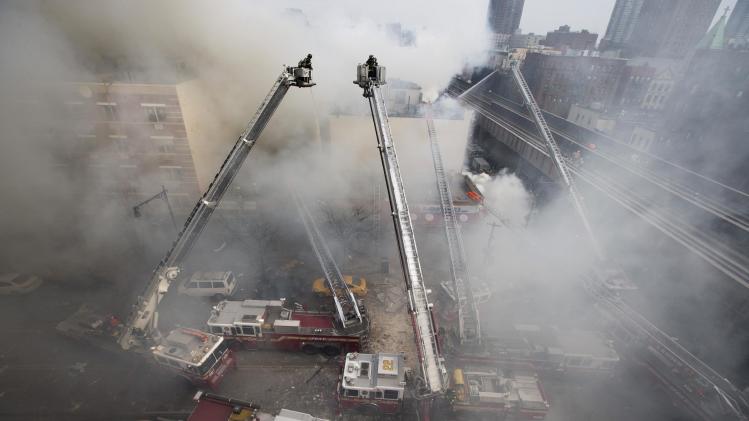Firefighters respond to a fire on 116th Street in Harlem after a building exploded in huge flames and billowing black smoke, leading to the collapse of at least one building and several injuries, Wednesday, March 12, 2014, in New York. (AP Photo/John Minchillo)