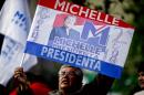 A supporter of Chile's former President Michelle Bachelet, who is running for reelection, holds up an image of her outside the hotel where she and her supporters await election results in Santiago, Chile, Sunday, Nov. 17, 2013. Bachelet left office with sky-high approval ratings after her 2006-10 presidency. (AP Photo/Victor R. Caivano)