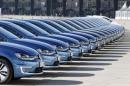 People pass row of Volkswagen e-Golf cars during company's annual news conference in Berlin