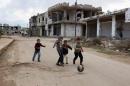 Children play near damaged buildings in the rebel held historic southern town of Bosra al-Sham, Deraa