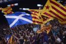 A fan waves a Scottish national flag alongside others waving 'Estelada' flags, that symbolize Catalonia's independence during the Champions League Group F soccer match between Barcelona and Apoel at the Camp Nou stadium in Barcelona, Spain, Wednesday, Sept. 17, 2014. (AP Photo/Manu Fernandez)