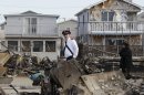 A representative of the Salvation Army walks past homes destroyed by Superstorm Sandy in Breezy Point, Sunday, Nov. 4, 2012, in New York. The beachfront neighborhood heavy populated by firefighters and police officers was devastated during the storm when a fire pushed by Sandy's raging winds destroyed 100 or more homes and buildings. (AP Photo/Kathy Willens)