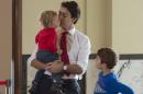 Liberal leader Justin Trudeau kisses his son, Hadrien, as son Xavier looks on while they wait to vote at a polling station Monday, Oct. 19, 2015 in Montreal. Canadians voted Monday to decide whether to extend Conservative Prime Minister Stephen Harper's near-decade in power or return Canada to its more liberal roots. (Adrian Wyld/The Canadian Press via AP) MANDATORY CREDIT
