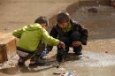 Children remove trash blocking the drains in the Al Inzarat district in Aleppo