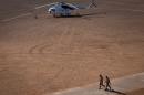 Soldiers walk near an United Nations helicopter on December 31, 2013 at a military base in Gao, northern Mali