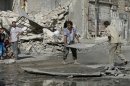 Civilians clean the streets from the debris of a building hit by a jet strike in the al-Meyasar district in Aleppo