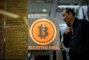 A man walks out of a shop displaying a bitcoin sign …