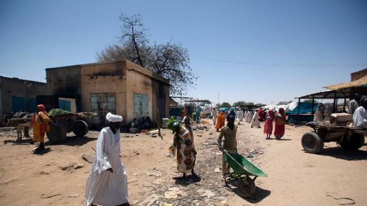 Sudanese people walk in the market area of Saraf Omra, North Darfur, which has some burnt buildings as a result of the inter-communal violence early this month on March 18, 2014