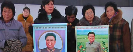 People, with photos of North Korean leader Kim Jong-il, stand near a monument at a square in Pyongyang in this   December 19, 2011 still image taken from video. (REUTERS/KCNA via Reuters TV)