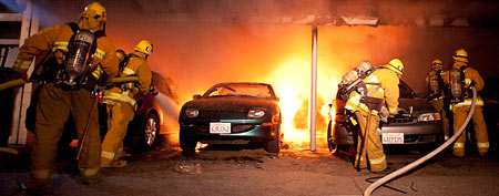Los Angeles Fire Department firefighters extinguish numerous cars fires in a carport in the Sherman Oaks neighborhood of Los Angeles on Monday, Jan. 2, 2012. (AP Photo/Dan Steinberg)