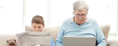 A young boy with a newspaper / old man on computer (Fotolia)