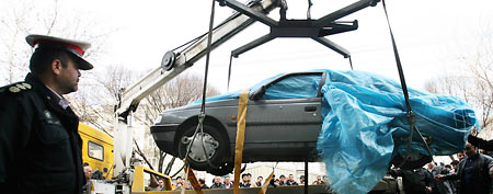 People gather around a car as it is removed by a mobile crane in Tehran. (AP/Fars News Agency, Mehdi Marizad)