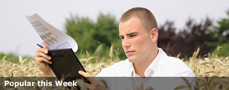 Young man looking at paperwork in a field (Thinkstock)