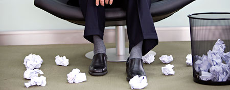 Executive with piles of crumpled papers (Corbis)
