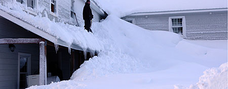 A man stands on a house buried in snow in the fishing town of Cordova, Alaska. (AP Photo/Alaska Division of Homeland Security and Emergency Management, Kim Weibl)