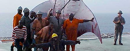 Oil derrick workers pose in front of a giant manta (GrindTV.com)