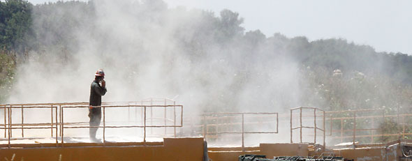 In this photo made on Wednesday, July 27, 2011, a worker stands on top of a storage bin as the dust of the powder used to make a mixture with water used in the hydraulic fracturing process in the Marcellus Shale layer to release natural gas billows above him at a Range Resources site where the process was underway in Claysville, Pa. (AP Photo/Keith Srakocic)