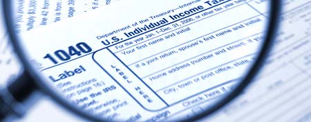 Magnifying glass over tax form (Thinkstock)