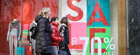 Pedestrians walk past a Gap store advertising up to 70 percent off regular prices on the day after Christmas in New York, Monday, Dec. 26, 2011. (AP Photo/Kathy Willens)