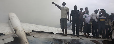People gather at the site of a plane crash in Lagos, Nigeria, Sunday, June 3, 2012. A passenger plane carrying more than 150 people crashed in Nigeria's largest city on Sunday, government officials said. (AP Photo/Sunday Alamba)