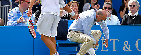 A line judge wipes blood from his injured leg after Argentina's David Nalbandian, left, kicked a small barrier surrounding the judge, leading to his disqualification during the Queen's Club grass court championships final tennis match against Croatia's Marin Cilic, London, Sunday, June 17, 2012. (AP Photo/Sang Tan)