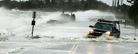 A truck drives through water pushed over a road by Hurricane Sandy in Southampton, New York (Reuters)