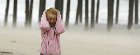 Molly White, 9, from Frankford, Del., covers her head as she is pelted by blowing sand on the beach, as Hurricane Sandy bears down on the East Coast, Sunday, Oct. 28, 2012, in Ocean City, Md. (AP Photo/Alex Brandon)