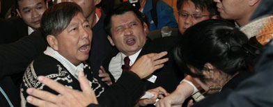 Hong Kong lawmaker and labour union representative Lee Chuck-yan (L) confronts security guards during a protest outside a commercial tower where the Singapore Consulate is located in Hong Kong December 5, 2012. The group demanded for the release of a Chinese immigrant bus driver being sentenced to jail in Singapore after a protest in late November. REUTERS/Bobby Yip