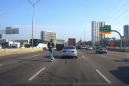 Dashcam captures man riding  a Lime scooter on the highway during rush hour