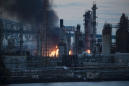 The Latest: Refinery fire controlled but still burning